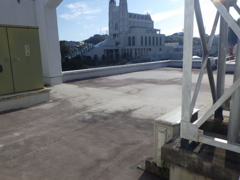 屋上防水塗装前の陸屋根シート防水の状態。奥に見える建物は結婚式場、迎賓館です。